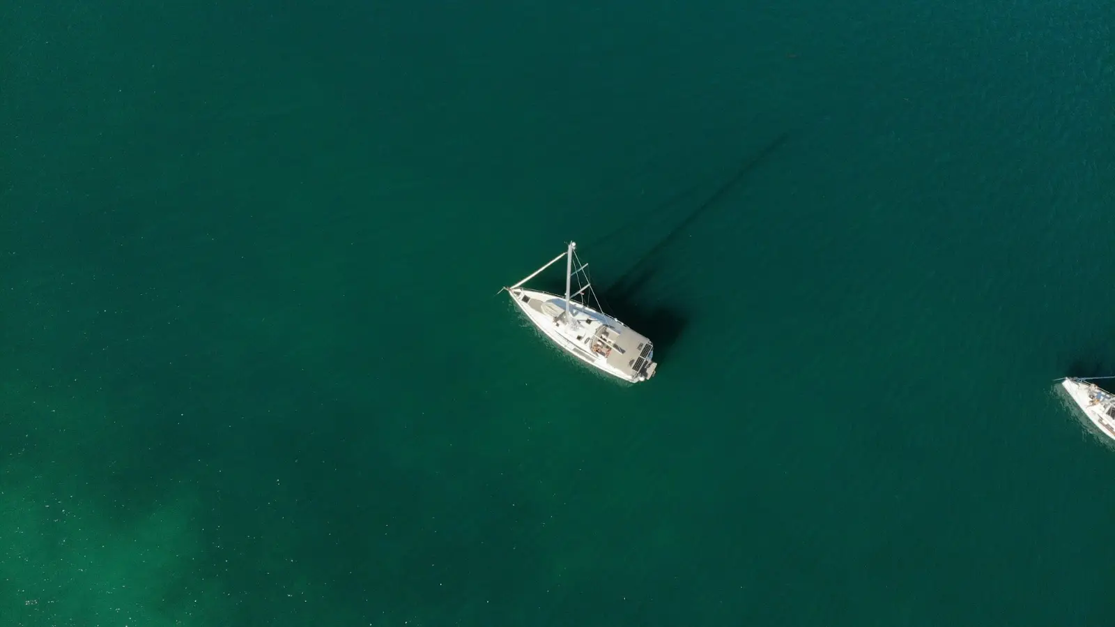 Top-down drone view of a yacht in turquoise water